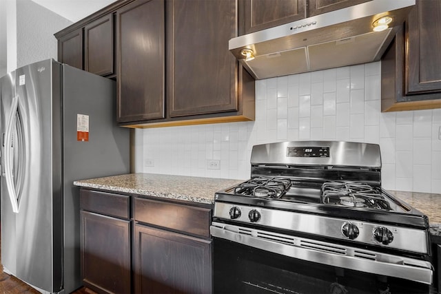 kitchen featuring range hood, decorative backsplash, dark brown cabinetry, stainless steel appliances, and light stone counters