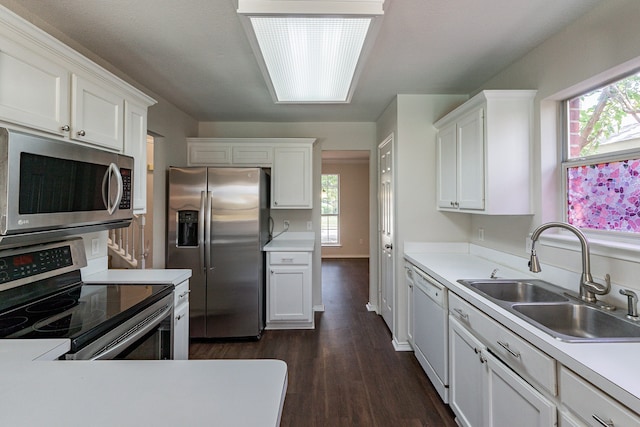 kitchen with appliances with stainless steel finishes, a healthy amount of sunlight, sink, and dark wood-type flooring