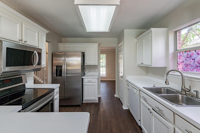 kitchen featuring appliances with stainless steel finishes, sink, white cabinets, and dark hardwood / wood-style floors