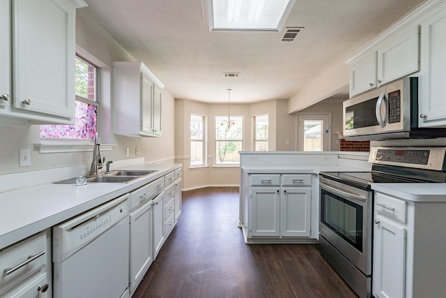 kitchen with decorative light fixtures, stainless steel appliances, white cabinets, dark hardwood / wood-style floors, and kitchen peninsula