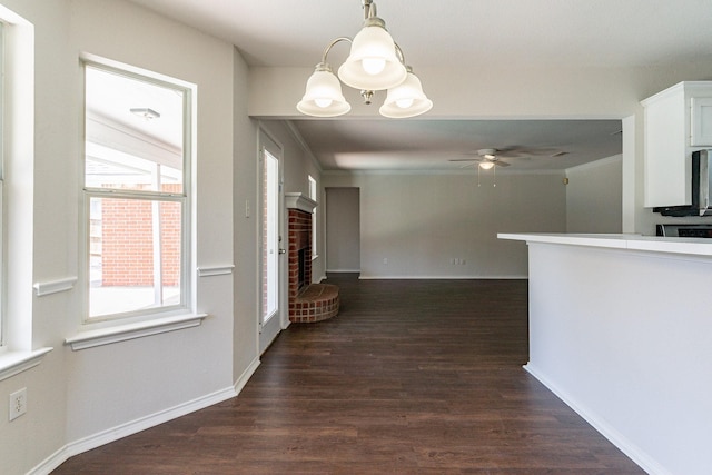 interior space featuring dark wood-type flooring, ceiling fan, a fireplace, and crown molding