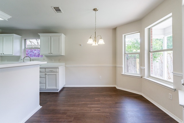 kitchen with an inviting chandelier, dark hardwood / wood-style floors, hanging light fixtures, and white cabinets