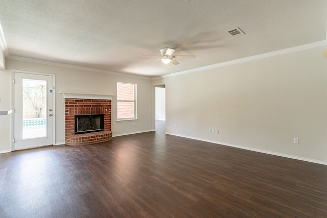 unfurnished living room featuring crown molding, a textured ceiling, dark wood-type flooring, ceiling fan, and a brick fireplace