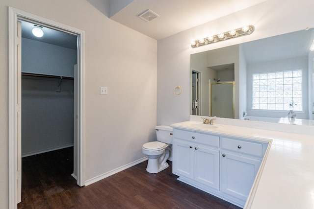 bathroom with hardwood / wood-style flooring, vanity, toilet, and walk in shower