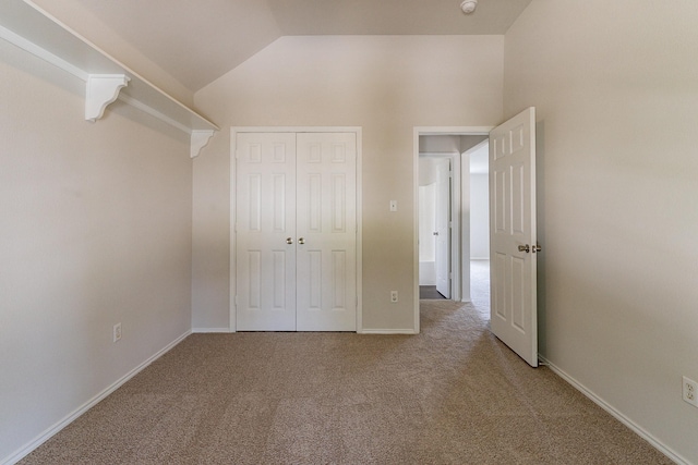 unfurnished bedroom featuring vaulted ceiling, carpet flooring, and a closet