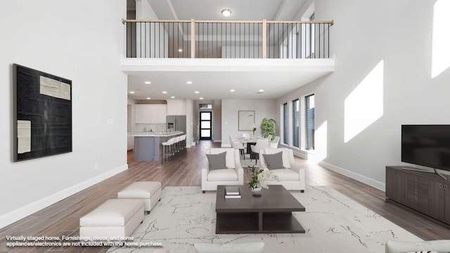 living room with a towering ceiling, hardwood / wood-style floors, and sink