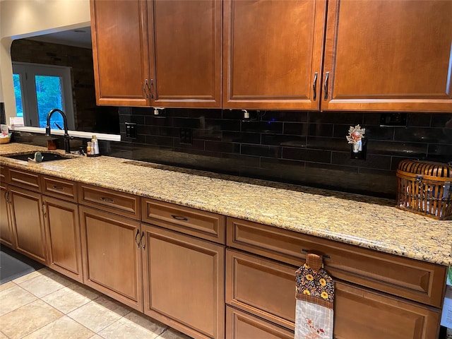 kitchen with sink, light tile patterned flooring, decorative backsplash, and light stone countertops