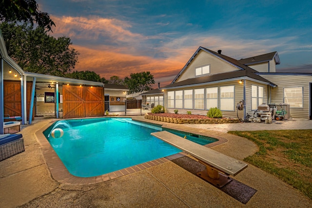 pool at dusk with a patio and a diving board