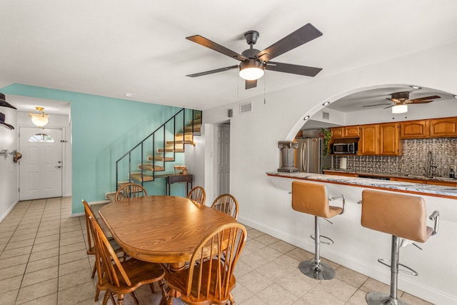 tiled dining space with ceiling fan and sink