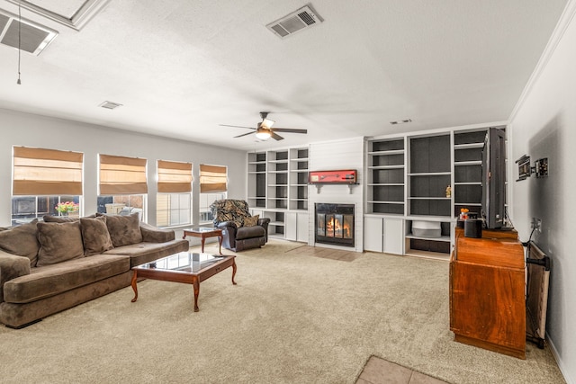 living room with a large fireplace, a textured ceiling, ceiling fan, built in features, and light colored carpet