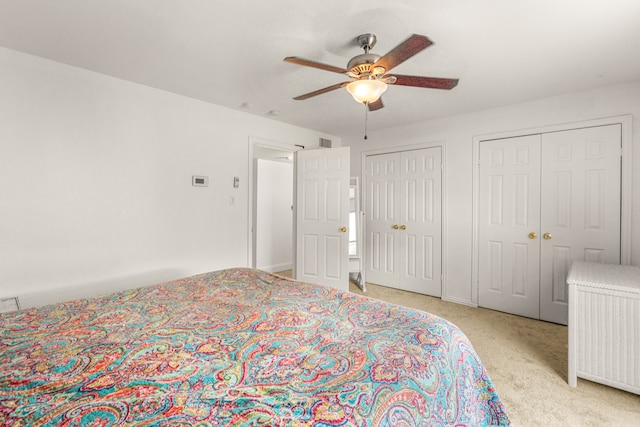 bedroom featuring ceiling fan, two closets, and light colored carpet