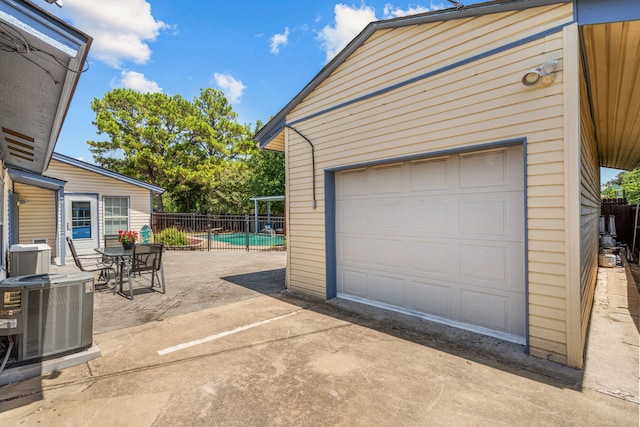 garage with a fenced in pool and central air condition unit