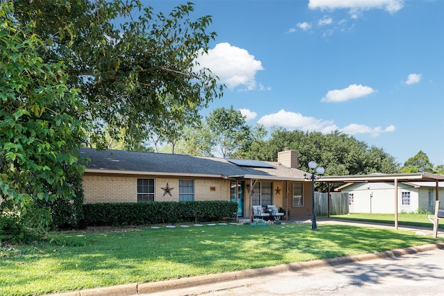 ranch-style home featuring solar panels and a front yard