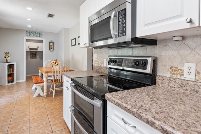 kitchen with light tile patterned floors, white cabinets, backsplash, light stone counters, and appliances with stainless steel finishes