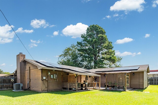 rear view of property with solar panels, a yard, central AC, and a patio area