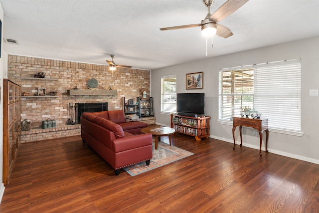 living room with ceiling fan, brick wall, a brick fireplace, and hardwood / wood-style floors