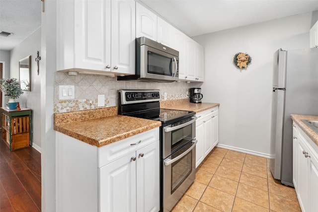 kitchen featuring decorative backsplash, appliances with stainless steel finishes, light wood-type flooring, and white cabinets