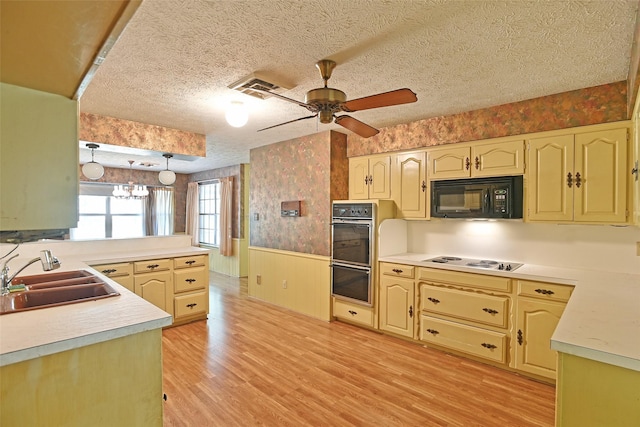 kitchen featuring kitchen peninsula, decorative light fixtures, a textured ceiling, black appliances, and sink