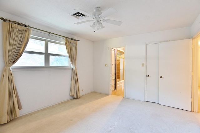 unfurnished bedroom with ceiling fan, connected bathroom, a closet, and light carpet