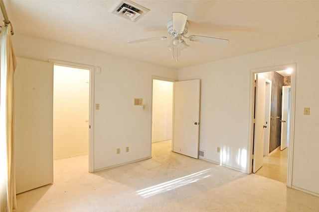 unfurnished bedroom with ceiling fan, a spacious closet, and light carpet