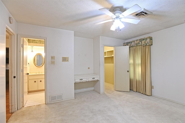 unfurnished bedroom featuring ceiling fan, light colored carpet, a spacious closet, and a closet