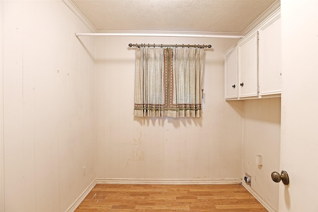 laundry area with a textured ceiling, light hardwood / wood-style flooring, crown molding, and hookup for an electric dryer