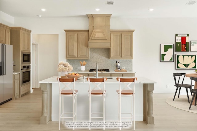 kitchen featuring a breakfast bar, decorative backsplash, stainless steel appliances, and a kitchen island with sink