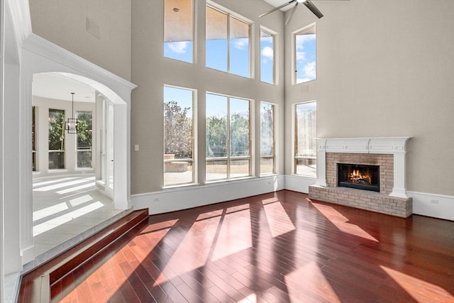 unfurnished living room with ceiling fan, a healthy amount of sunlight, a fireplace, and hardwood / wood-style floors