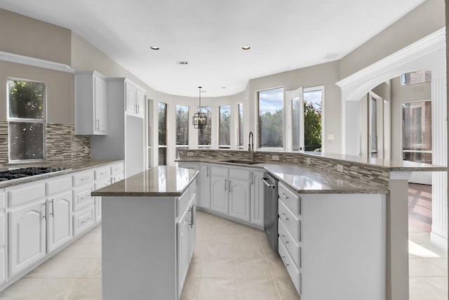 kitchen featuring sink, tasteful backsplash, dark stone countertops, a kitchen island, and white cabinets