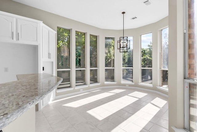 unfurnished sunroom featuring plenty of natural light and a notable chandelier