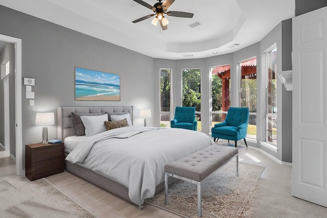 bedroom with access to exterior, a tray ceiling, and ceiling fan