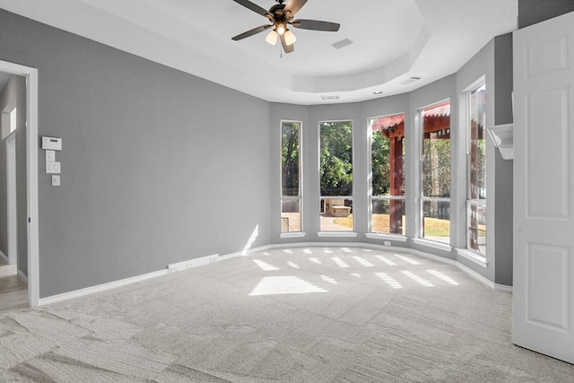 carpeted spare room featuring ceiling fan and a raised ceiling