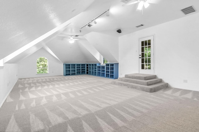 bonus room featuring light carpet, a textured ceiling, vaulted ceiling, and ceiling fan