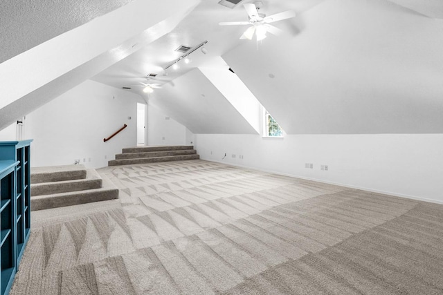 additional living space featuring vaulted ceiling, light carpet, a textured ceiling, and ceiling fan