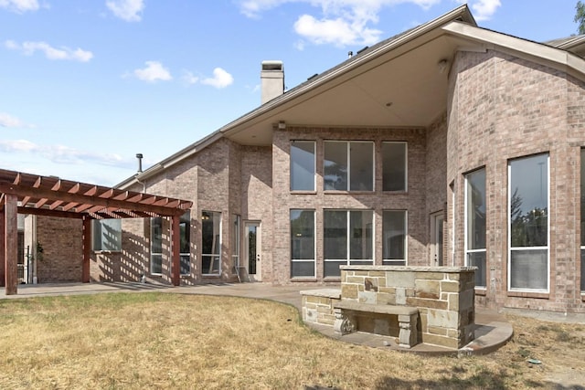 rear view of house featuring a pergola, a patio area, and a lawn