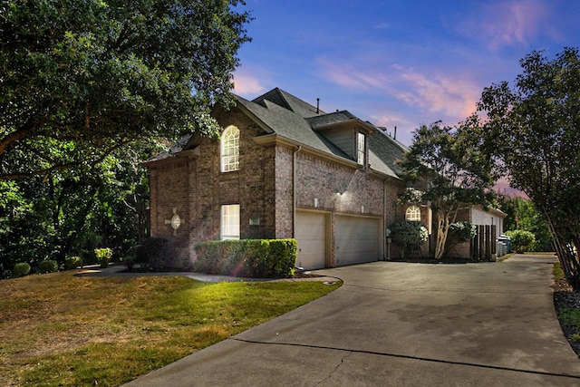 property exterior at dusk featuring a yard and a garage