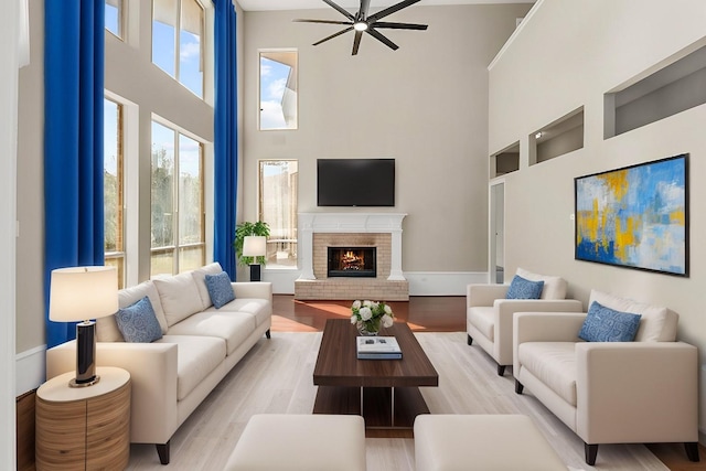 living room with a high ceiling, a brick fireplace, and light hardwood / wood-style flooring