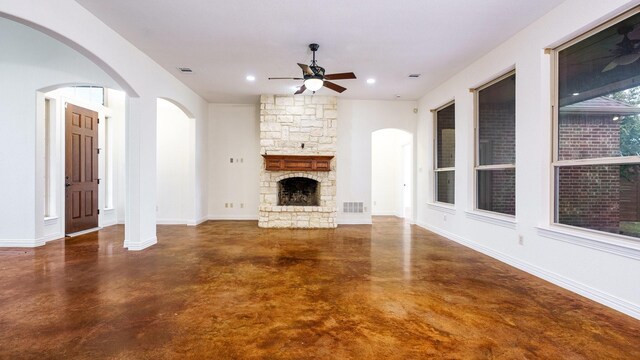 unfurnished living room with ceiling fan and a stone fireplace