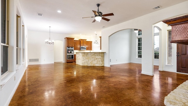 unfurnished living room featuring ceiling fan with notable chandelier