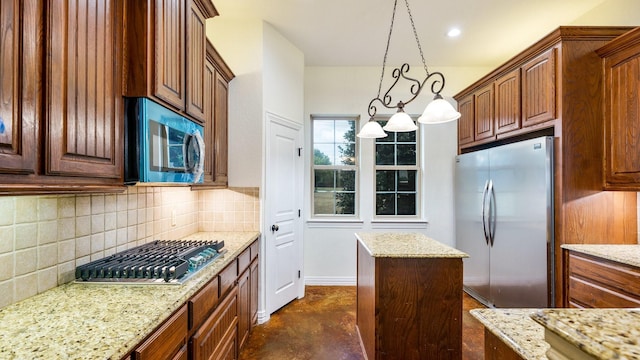 kitchen with light stone counters, appliances with stainless steel finishes, a kitchen island, and hanging light fixtures