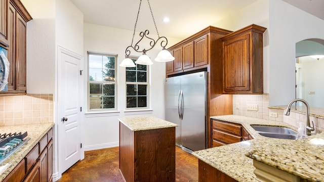 kitchen featuring appliances with stainless steel finishes, sink, pendant lighting, and light stone counters