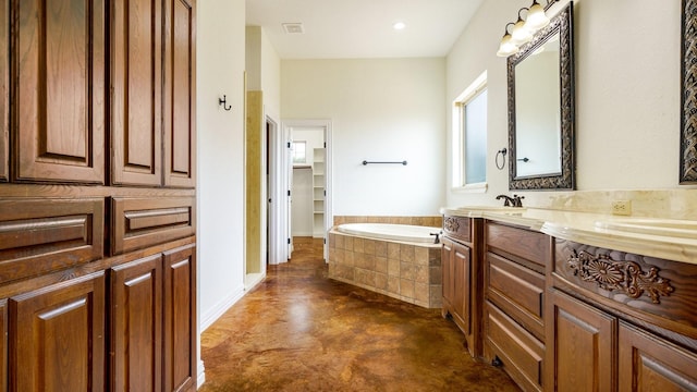 bathroom with concrete flooring, vanity, and tiled bath