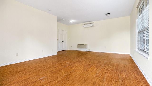 unfurnished room featuring hardwood / wood-style flooring and a wall mounted AC