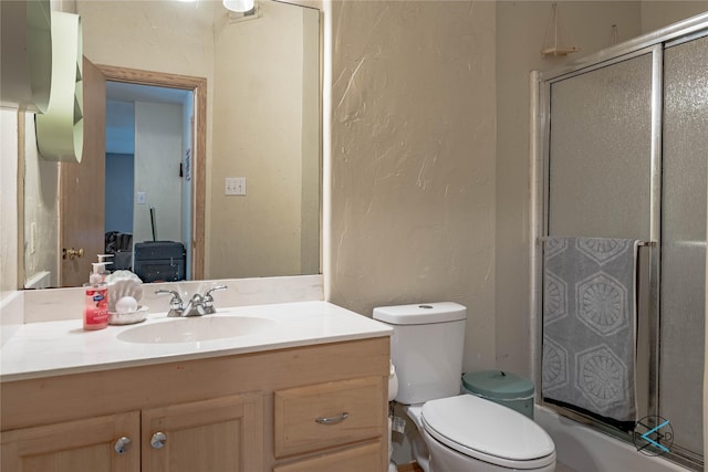 bathroom featuring a shower with shower door, toilet, and vanity