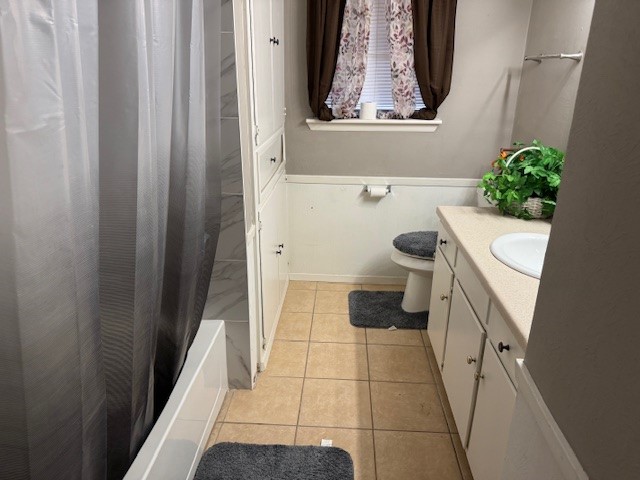 full bathroom with vanity, shower / bathtub combination with curtain, toilet, and tile patterned floors