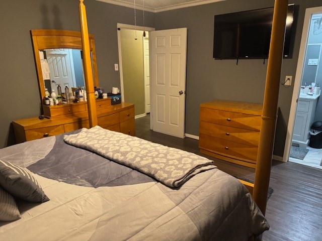 bedroom featuring ornamental molding, ensuite bathroom, and dark wood-type flooring