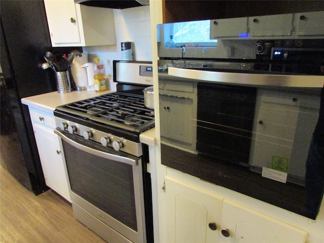 kitchen with light hardwood / wood-style flooring, range hood, backsplash, white cabinetry, and gas stove