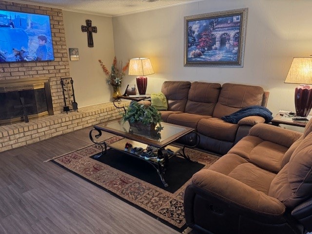 living room featuring ornamental molding, a textured ceiling, a brick fireplace, and wood-type flooring