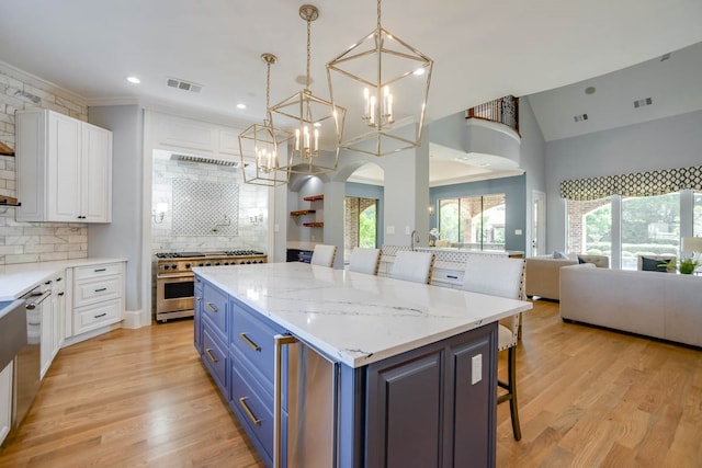 kitchen with decorative backsplash, white cabinetry, light hardwood / wood-style flooring, and double oven range