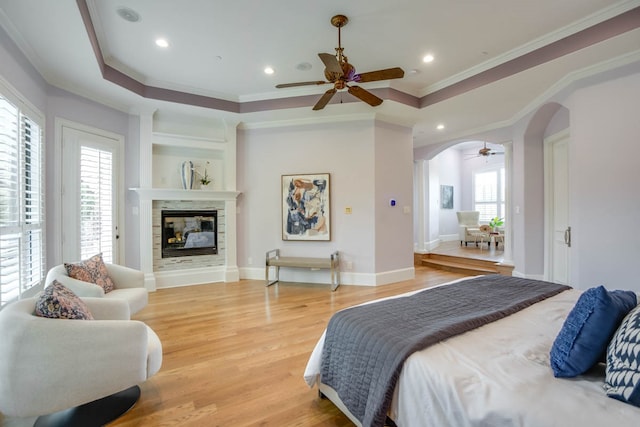 bedroom with ornamental molding, a multi sided fireplace, multiple windows, and hardwood / wood-style floors